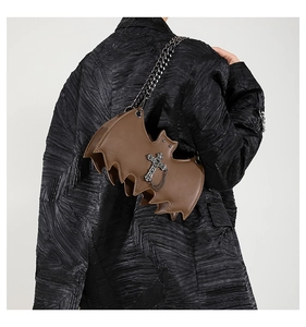 Detailed view of the brown bat-shaped crossbody bag with gothic silver chain on a model