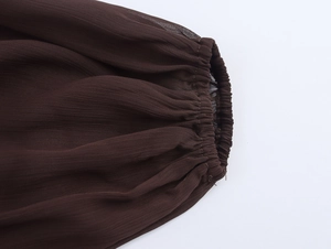 Detailed close-up of dark brown elastic cuffs and pleated fabric texture on long sleeve dress