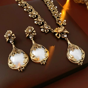Gros plan d'un pendentif fleur vintage et de boucles d'oreilles perles sur cuir brun