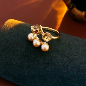 Detail of gold-plated ring with pink pearls and champagne crystals on green velvet