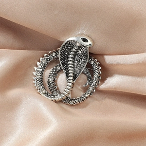 Detailed close-up of a silver cobra snake brooch with micro-pave crystals on silk fabric