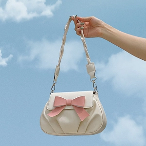 Sac bandoulière plissé chic avec nœud rose et bandoulière tressée sur fond de ciel