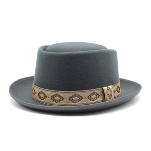 Detail view of grey wool pork pie hat featuring a brown geometric embroidered hatband