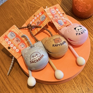 Three cute Capybara Panda and Fish stress-relief keychains on warm orange background