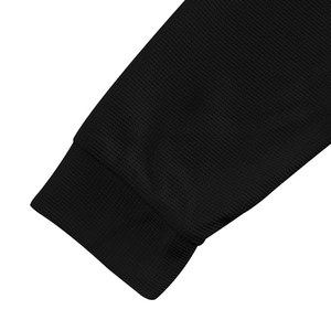 Close-up of black waffle knit texture and ribbed cuffs on a men's long sleeve Henley shirt