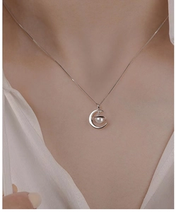 Detail of elegant 925 sterling silver moon and pearl pendant necklace worn by a female model