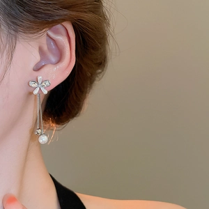 Close-up of silver tassel earrings with flower crystal studs and pearls on a model