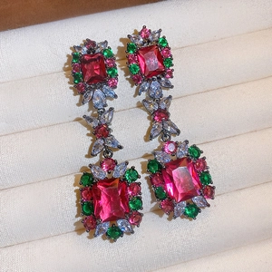Dettaglio di orecchini vintage con pietre rosa e verdi in una scatola portagioie