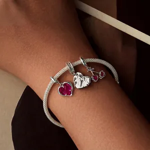 Silver mesh bracelet with ruby red heart and cherry charms on a female model wrist
