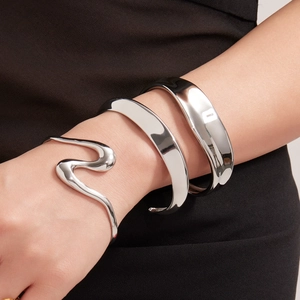 Conjunto de pulseras de acero inoxidable plateado para mujer sobre fondo de ropa negra