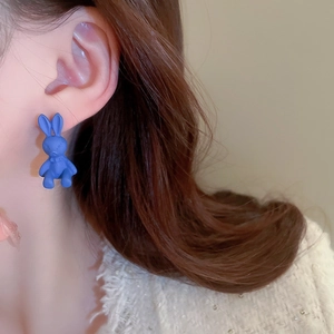 Close-up of a blue flocking rabbit stud earring worn on ear with soft matte texture