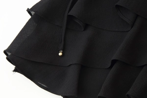 Detailed close-up of black ruffled fabric texture with a gold metal bead drawstring detail