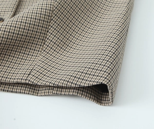 Détail de près du tissu à carreaux kaki montrant la texture sergée fine et les coutures nettes
