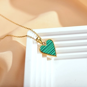 Detailed macro view of heart pendant featuring green stripes and a gold plated chain