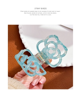 Detail of blue hollowed camellia flower hair claw clip with acetate finish and metal spring