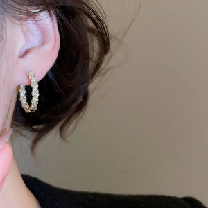 Gros plan de boucles d'oreilles dorées de luxe avec incrustations de zircons et nacre