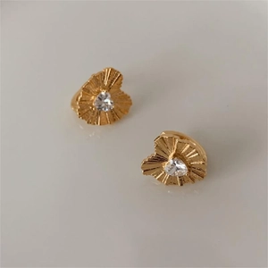 Detailed close-up of golden heart earrings with pleated texture and zircon stones