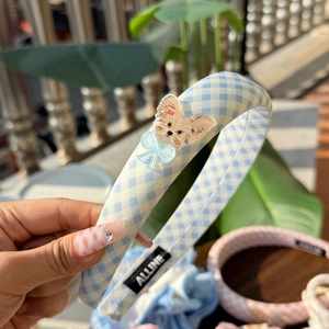 Detail of blue and white checkered fabric headband with cute dog charm and bow