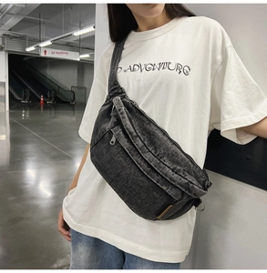 Detailed view of a vintage black denim crossbody bag featuring multiple zipper pockets