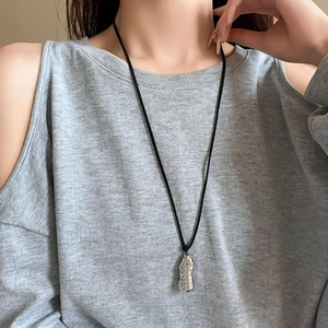 Macro shot of a creative peanut-shaped silver pendant necklace on a minimalist black cord