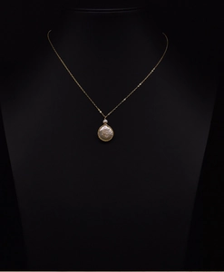 Detail shot of a minimalist gold chain necklace with a baroque pearl pendant on black model
