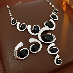 Detailed view of a silver geometric necklace with multiple black oval gemstone inlays