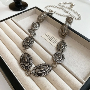 Detailed macro view of silver oval engraved metal links and clasp in a beige velvet jewelry box