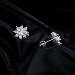 S925 silver snowflake stud earrings with 0.4ct moissanite stones on black leather