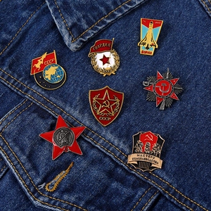 Close-up of Soviet-themed metal enamel pins including CCCP and Red Star on denim jacket