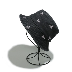 Detail of pink embroidered bows on black washed denim bucket hat with metal stand