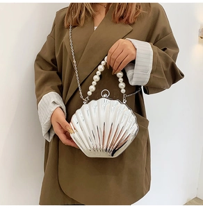 Detailed view of silver shell-shaped bag with pearl handle and metal chain strap