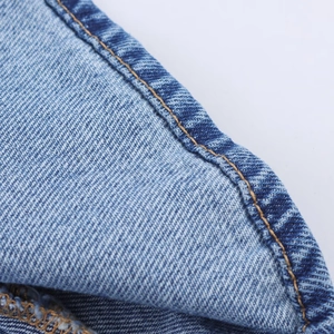 Nahaufnahme von blauem Denim-Stoff mit Doppelsteppnähten und Twill-Textur-Details