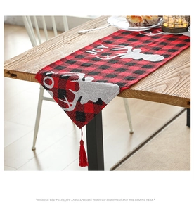 Close-up of Christmas table runner featuring red plaid fabric with elk motif and red tassels