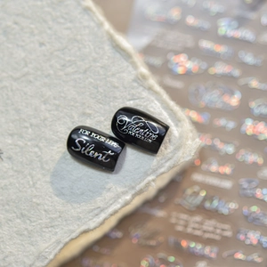Vue macro d'ongles noirs avec des lettres anglaises argentées imprimées au laser brillant
