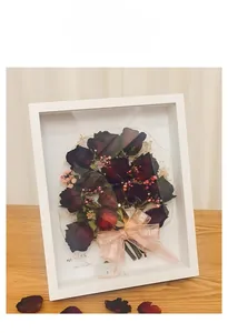 Detail of white 3D shadow box frame with dried red roses and FOR YOU pink ribbon