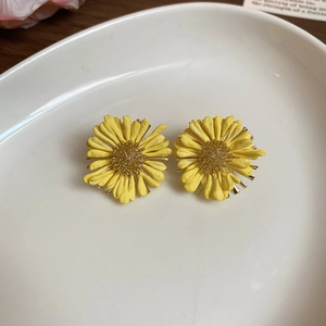 Detailed close-up of yellow daisy stud earrings with golden wire center in a ceramic dish
