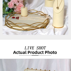 Detailed shot of gold jewelry display stands and pearl necklace on white silk background