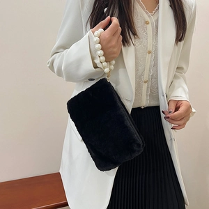 Elegant black faux fur small square bag with white pearl handle strap worn by a model