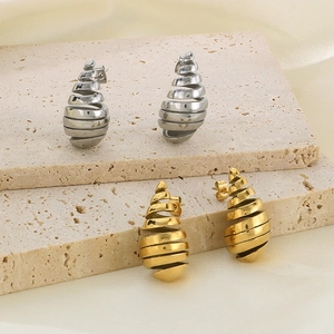Macro shot of spiral cone earrings in gold and silver finish on textured stone