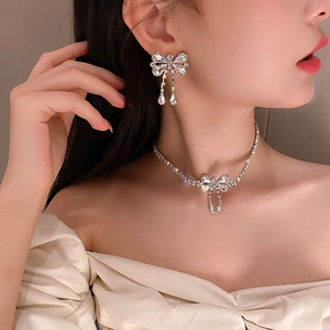 Elegant silver rhinestone bow necklace and earrings set worn by a fashion model