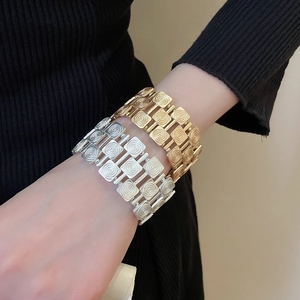 Detail of wide metallic textured bracelet set in gold and silver with spiral patterns