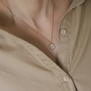 Minimalist 18K gold plated necklace featuring a white shell starburst pendant on a model