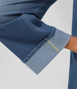 Dettaglio dell'orlo risvoltato su un jeans in denim blu a gamba dritta con cuciture