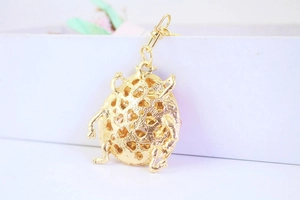 Macro shot of golden beetle keychain with heart-shaped cutouts on metal surface