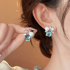 Eleganti orecchini geometrici con zircone blu e perla indossati per un look raffinato