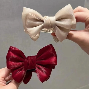 Detail of satin bow hair claws in beige and burgundy colors for elegant updos