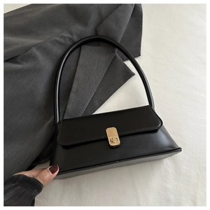 Detail of a vintage black PU leather shoulder bag with a gold metal clasp on a soft background