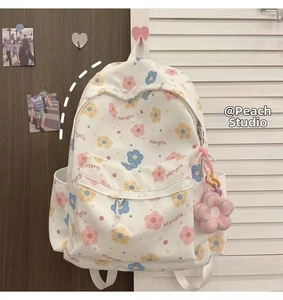 Close-up of floral print backpack featuring side pockets and pink flower plush charm