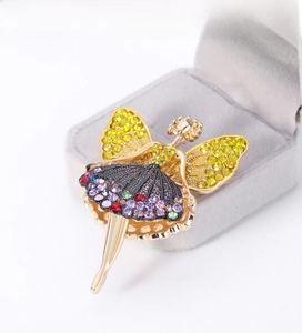 Detailed close-up of a golden ballet girl brooch featuring colorful rhinestones