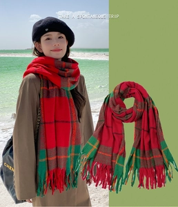 Detail of red and green plaid scarf featuring decorative tassels and soft knit texture